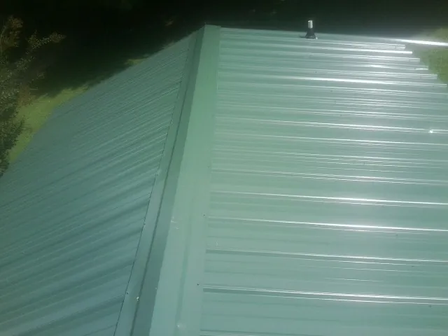 New green metal panels meeting at the ridge of a roof — Flat Roof Repair work by our crew in Beccaria