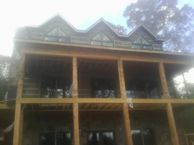 Dormers and porch framing on a large log home under construction — Roof Coating work by our crew in Beccaria