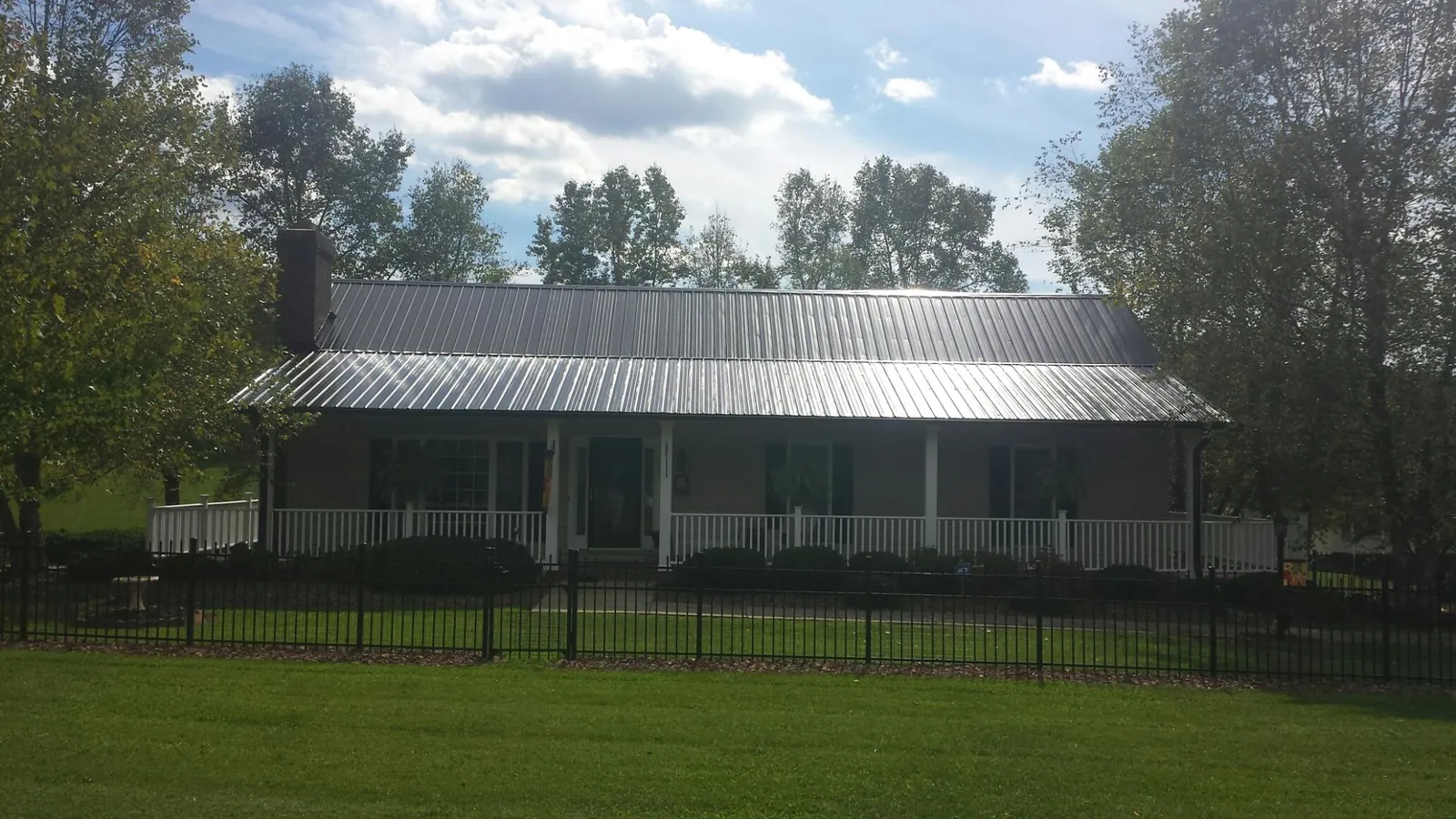 Gray metal roof on a brick ranch with a full width front porch — Gutter Guard Installation work by our crew in Beccaria